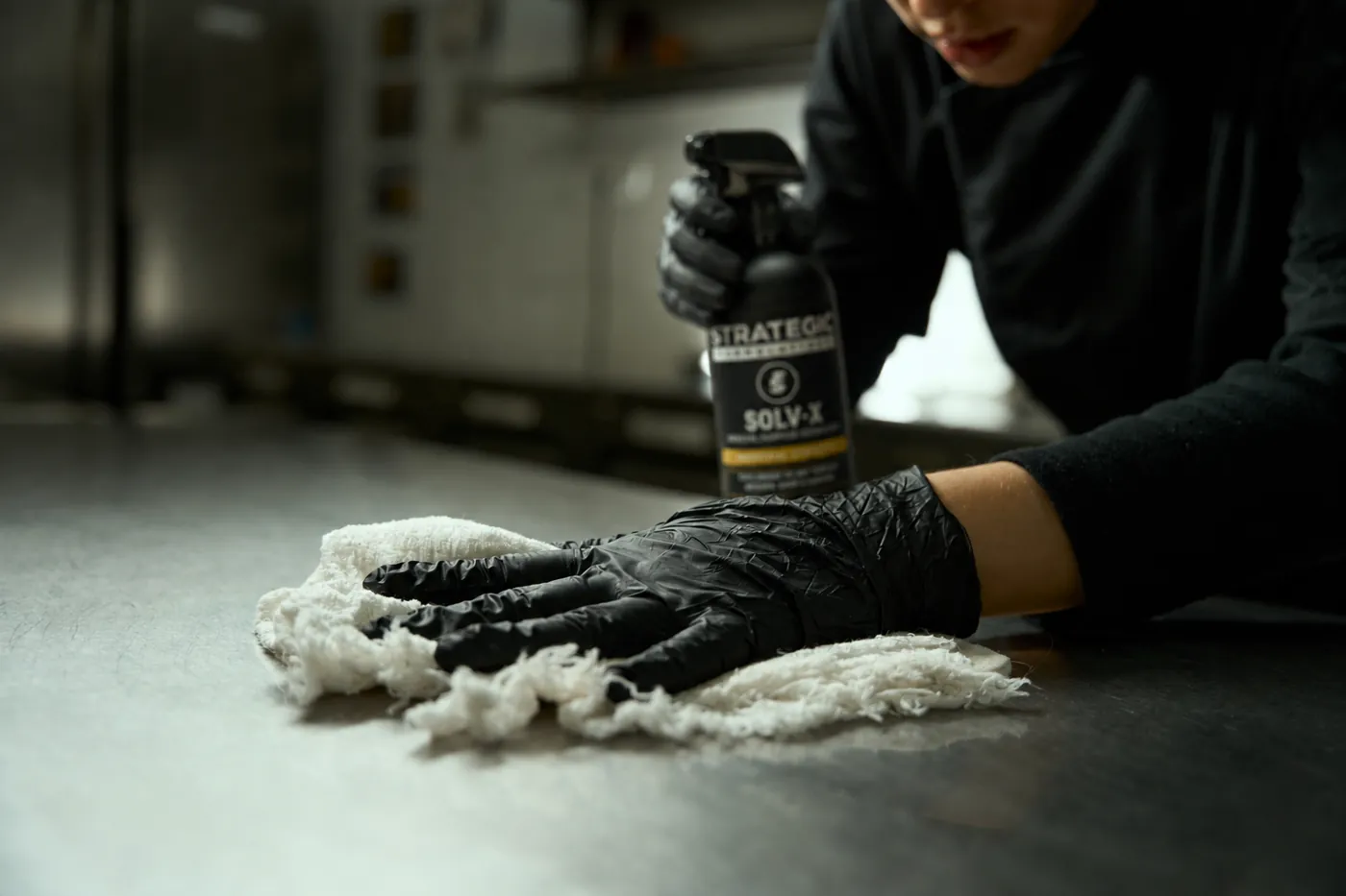 Wiping down a stainless prep line with SOLV-X in a commercial kitchen